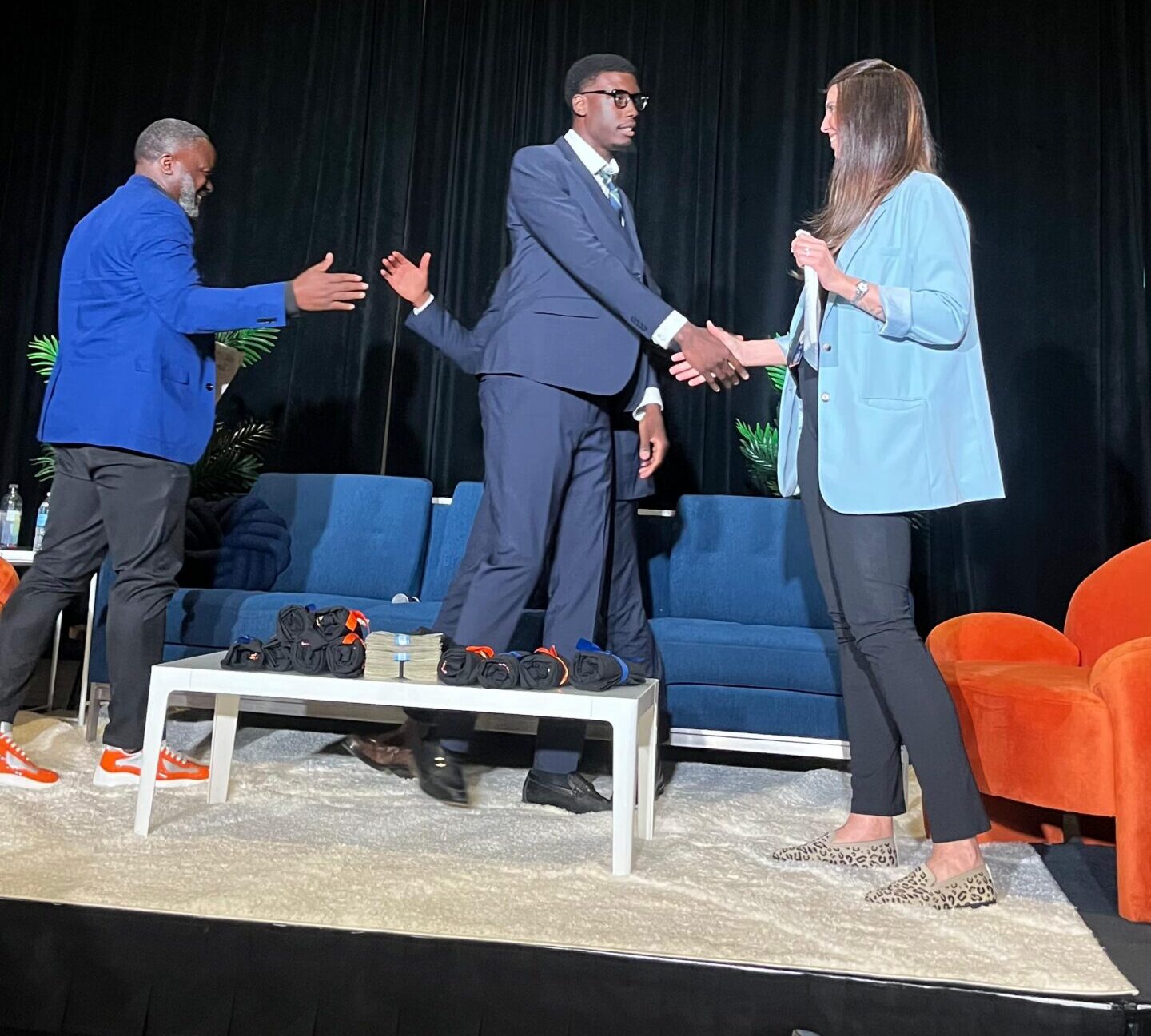 Business professionals greeting one another onstage during a panel event